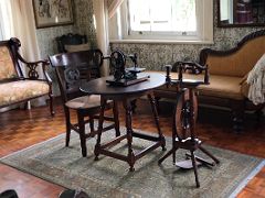 10 The Ladys sewing room has a sewing machine on a wooden table and a fainting chair Devon House mansion Kingston Jamaica